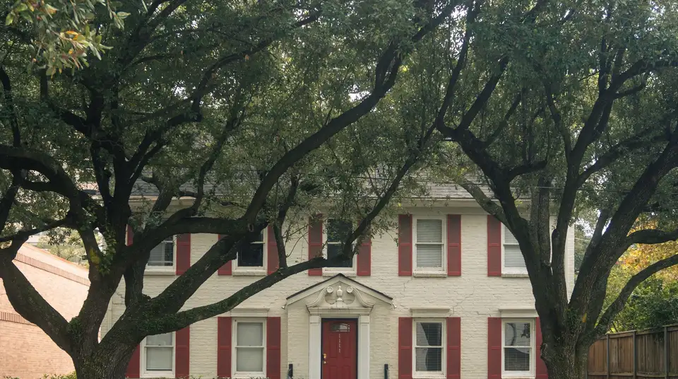 Plumber arriving at a brick ranch home in Waco under a pecan tree