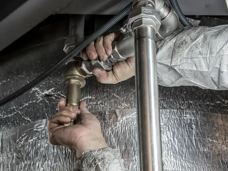 Plumber repairing a leaking pipe inside a wall